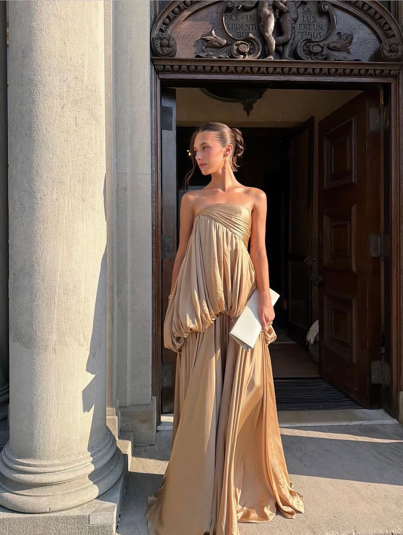 a champagne pleated column gown by a stone doorway