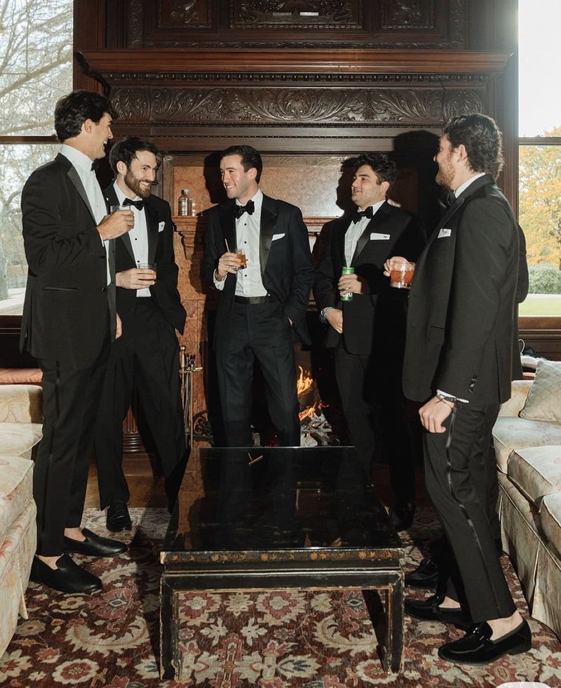 gentlemen in black tie by a carved fireplace